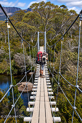 Hikers crossing the suspension bridge across the Narcissus River on the Windy Ridge to Narcissus segment of the Overland Track in Tasmania